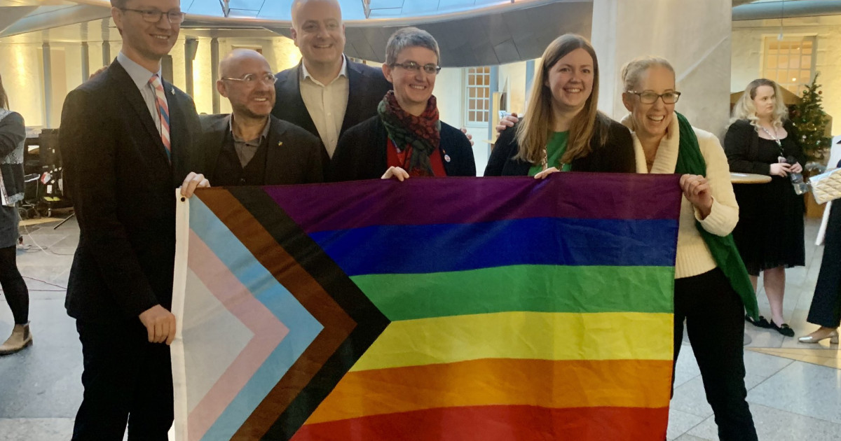 Scottish Green MSP holding the pride flag in the Scottish Parliament.