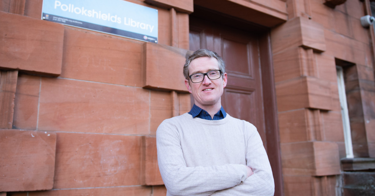 A picture of Glasgow Greens co-leader Cllr. Jon Molyneux standing in front of pollokshileds library.