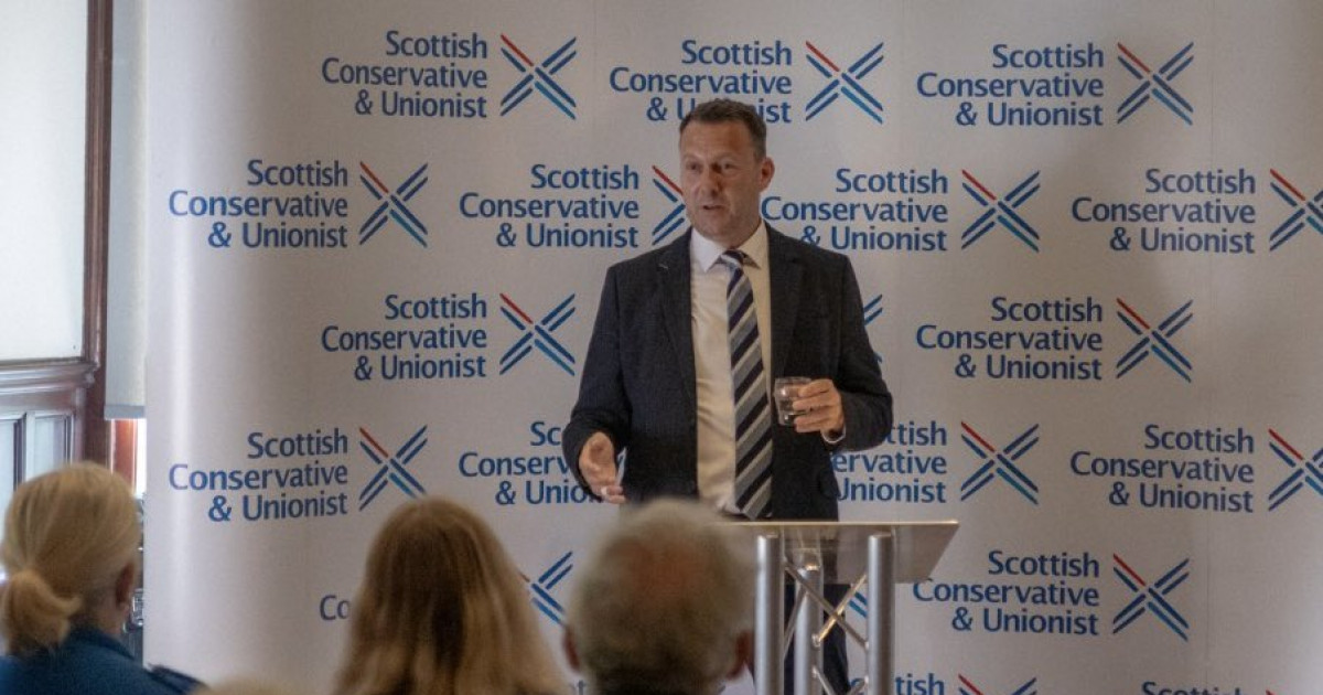 Russell Findlay speaks in front of a Scottish Conservative board.